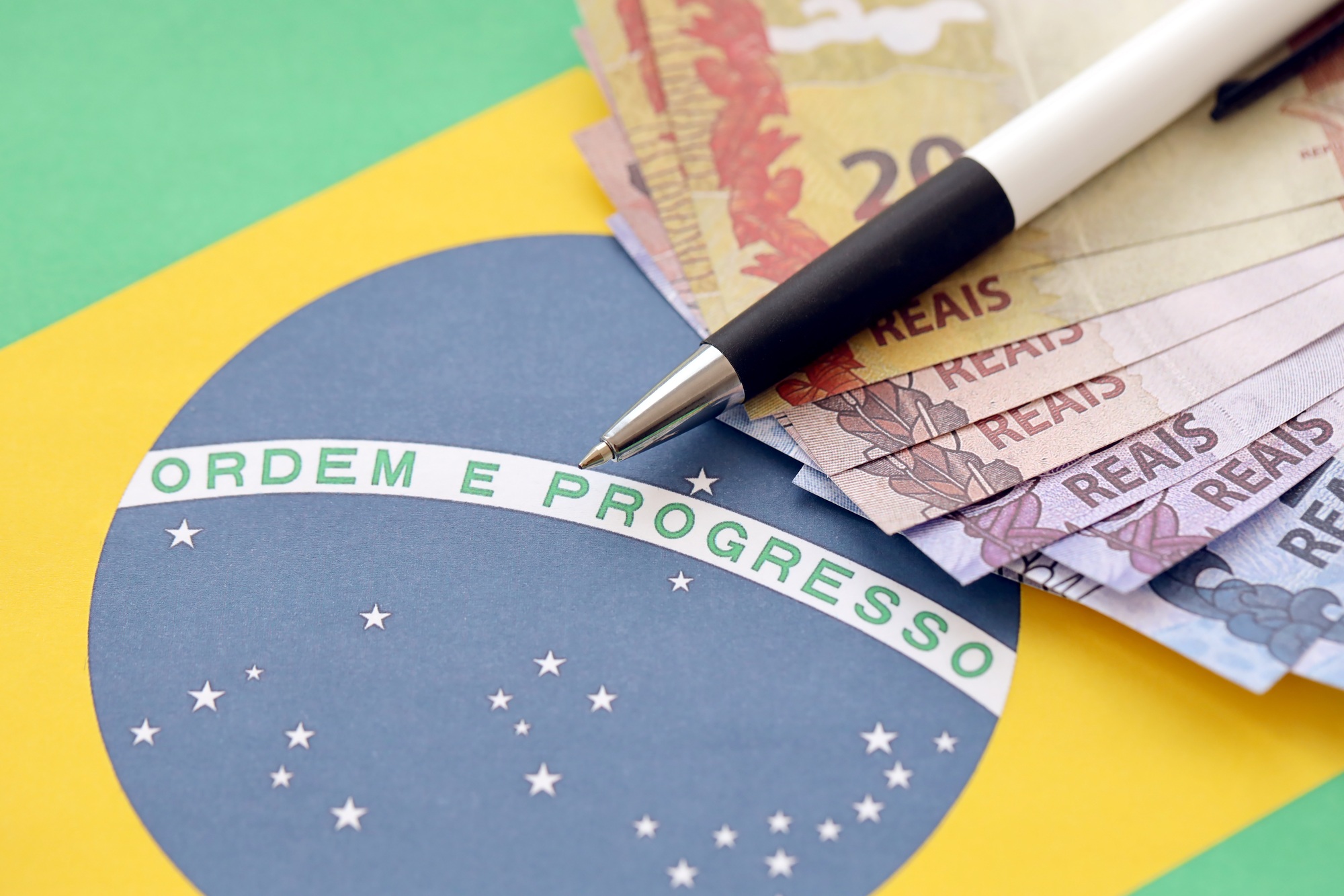 Pen with Brazilian money bills on blank of lottery game. Concept of luck and gambling in Brazil
